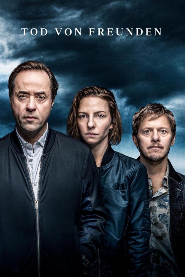 Das Filmplakat für „Tod von Freunden“ zeigt drei ernste Schauspieler vor einem dunklen Himmel.
