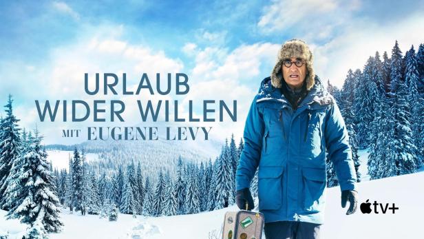 Eugene Levy in Winterkleidung und Pelzmütze vor einer verschneiten Winterlandschaft für „Urlaub wider Willen“.