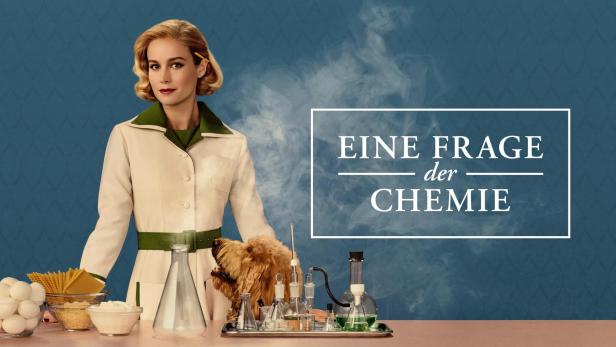 Eine Frau im Laborkittel steht mit einem Hund und Laborutensilien vor dem Schriftzug „Eine Frage der Chemie“.