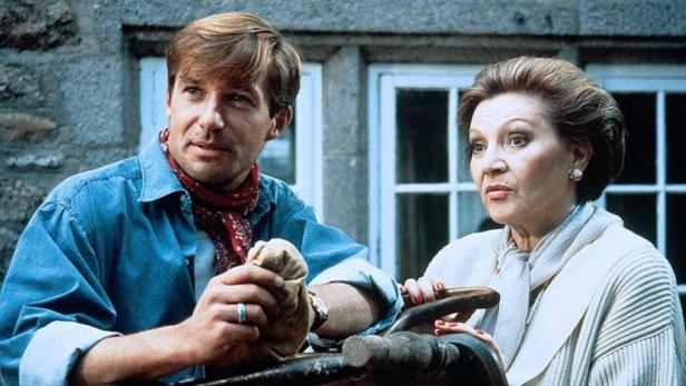 Ein Mann und eine Frau stehen vor einem Haus mit Sprossenfenstern.