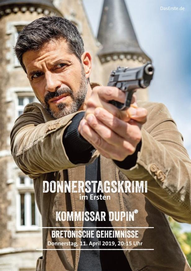 Kommissar Dupin zielt mit einer Pistole vor einem Schloss.