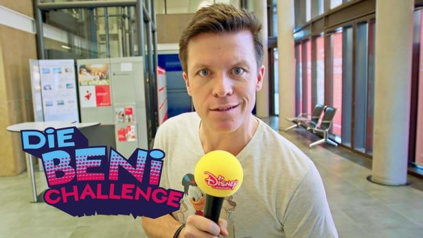 Ein Mann hält ein Mikrofon des Disney Channels in der Hand, im Hintergrund steht „Die Beni Challenge“.