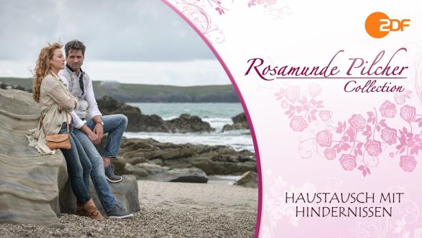 Ein Paar sitzt am Strand auf einem Felsen, im Hintergrund das Meer.