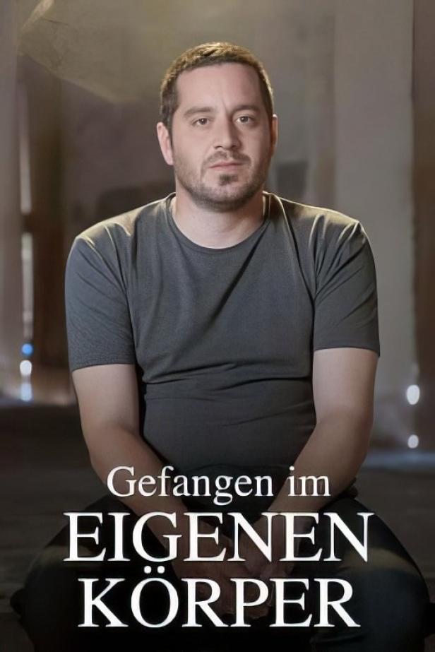 Ein Mann vor dem Titelbild von „Gefangen im eigenen Körper“.