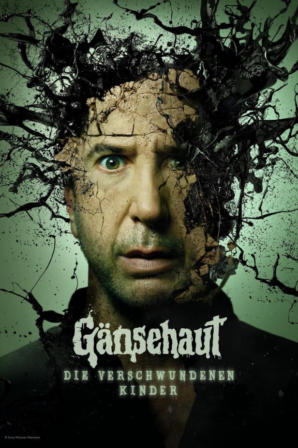 Ein Mann mit besorgtem Blick, dessen Gesicht teilweise von Rissen und schwarzer Farbe bedeckt ist, für „Gänsehaut: Die verschwundenen Kinder“.