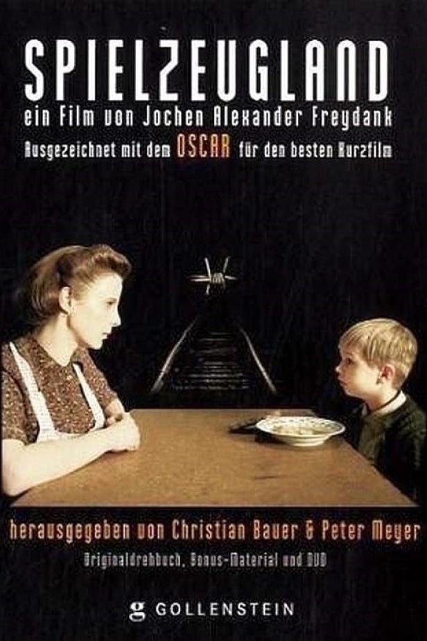 Das Filmplakat für „Spielzeugland“ zeigt eine Frau und einen Jungen an einem Tisch vor Bahngleisen.