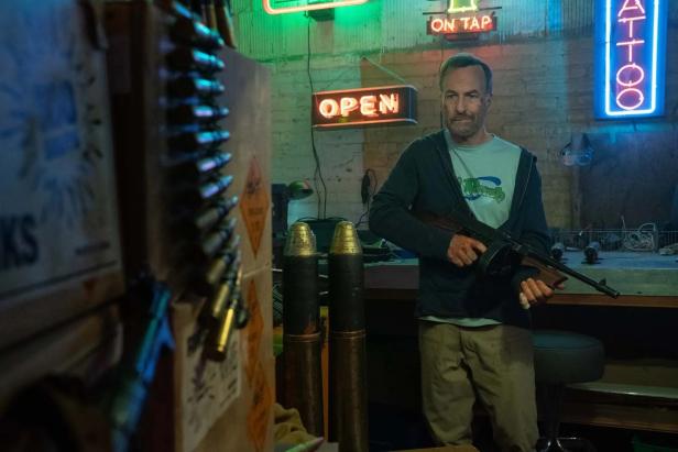 Bob Odenkirk steht mit Feuerwaffe in der Hand in „Nobody 2“ in einem Hinterraum.