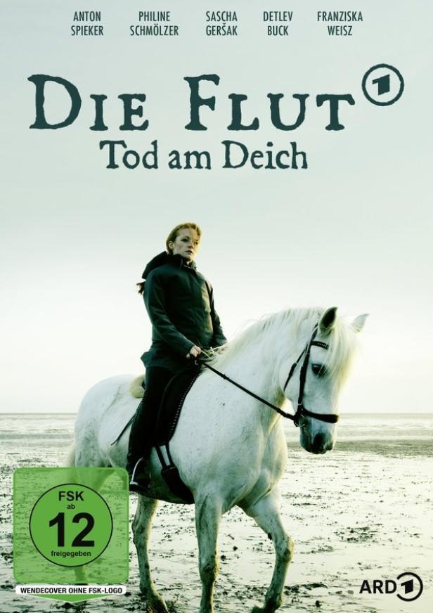 Eine Frau reitet auf einem weißen Pferd am Strand; Filmposter für „Die Flut – Tod am Deich“.