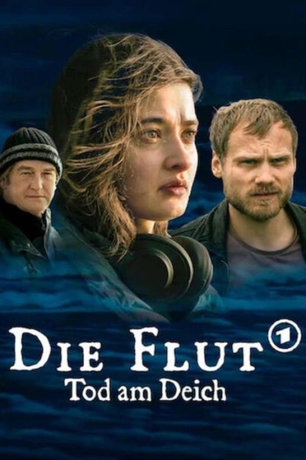 Das Filmplakat für „Die Flut – Tod am Deich“ zeigt drei Schauspieler vor blauem Hintergrund.