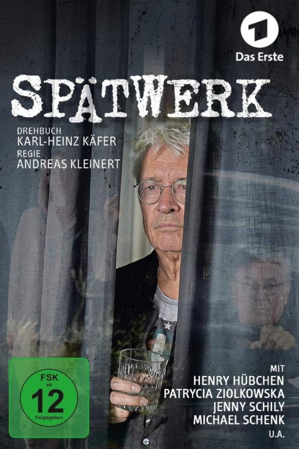 Das Filmplakat zu „Spätwerk“ zeigt einen Mann mit einem Glas in der Hand hinter einem Vorhang.
