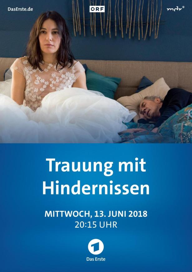 Eine Frau im Brautkleid sitzt neben einem schlafenden Mann im Bett.