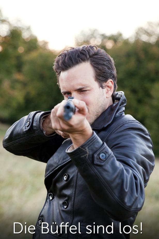 Ein Mann im Ledermantel zielt mit einem Gewehr.