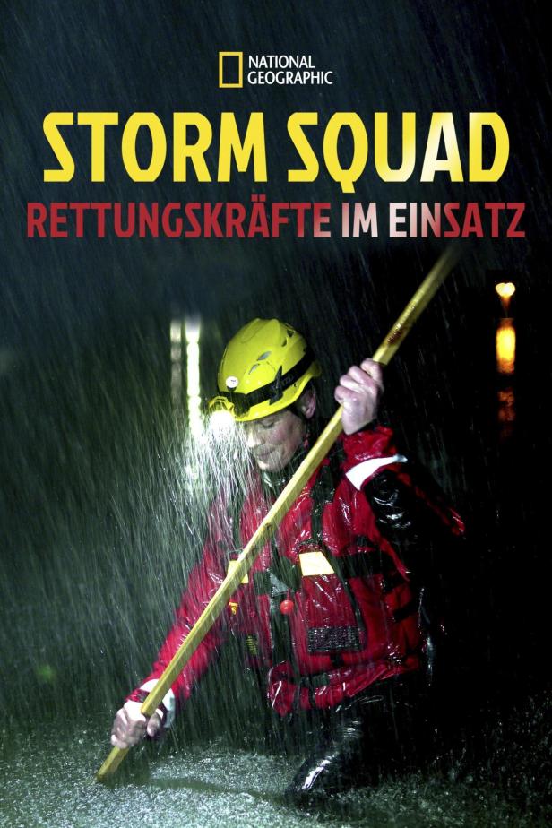 Ein Mitglied des „Storm Squad“ watet im Regen mit einem Stab durch das Wasser.