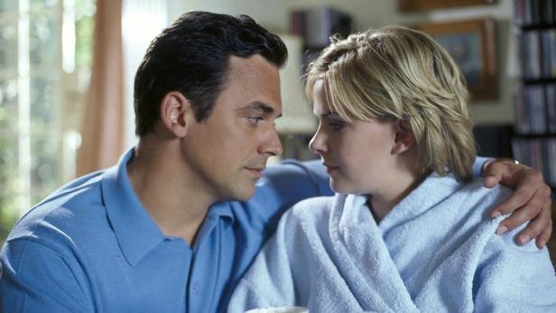 Ein Mann und eine Frau sehen sich liebevoll an, sie trägt einen Bademantel.