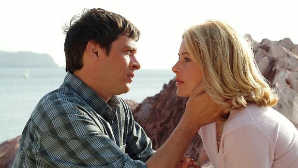 Ein Mann und eine Frau sehen sich am Meer liebevoll in die Augen.