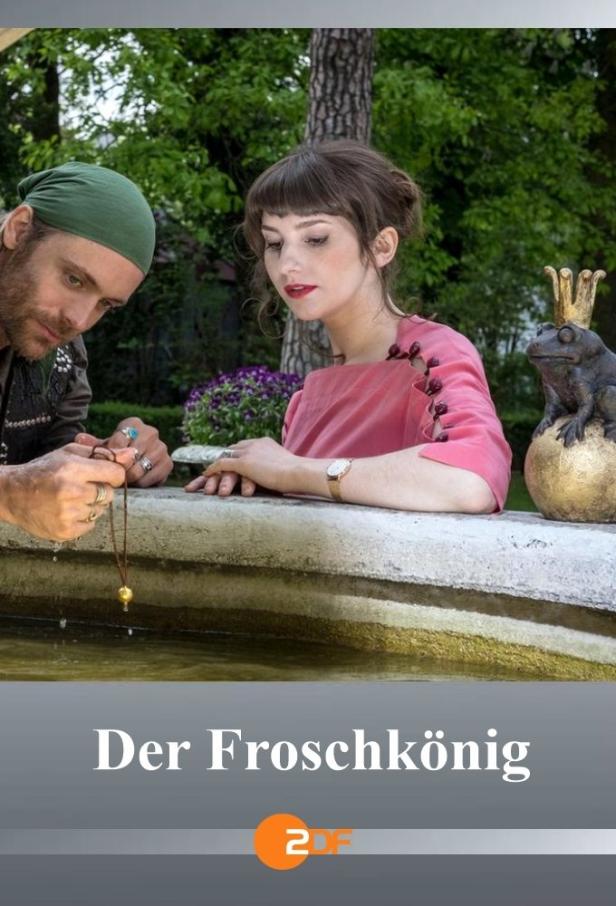 Ein Mann und eine Frau am Brunnen mit einer Froschstatue mit Krone.