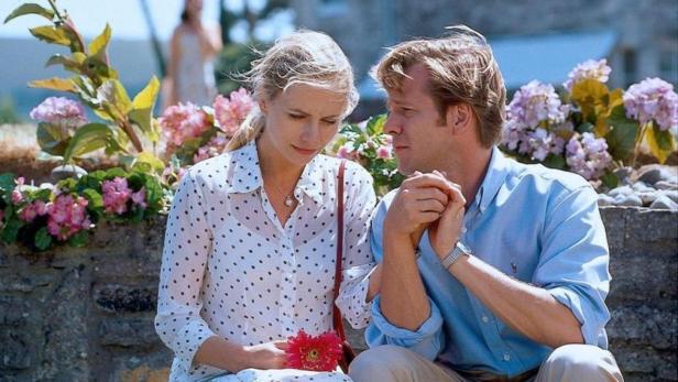 Ein Paar sitzt vor einem Blumenbeet und unterhält sich.