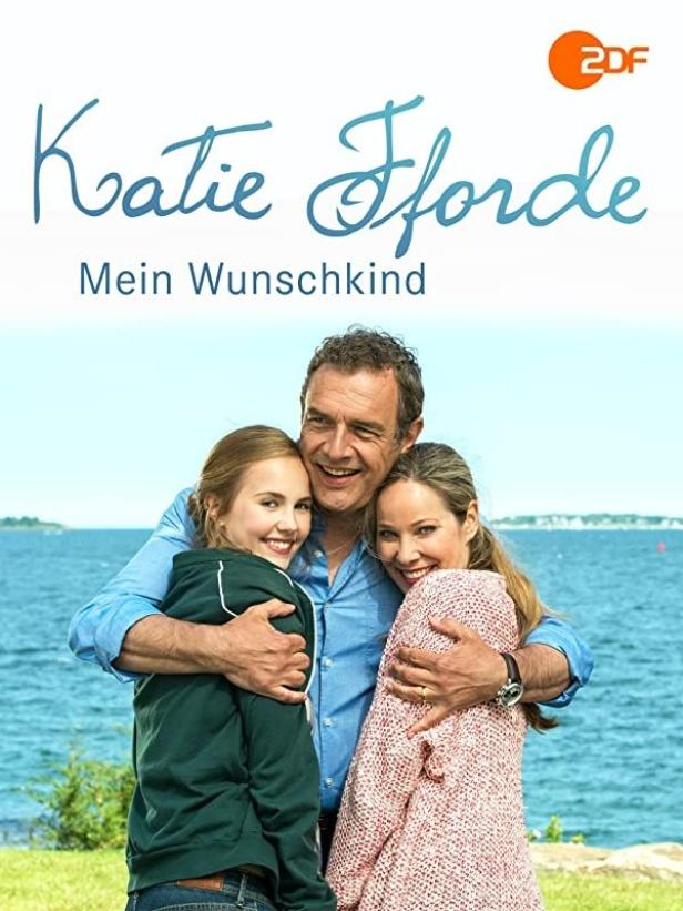 Das Filmplakat zu „Katie Fforde: Mein Wunschkind“ zeigt einen Mann, der zwei junge Frauen umarmt.