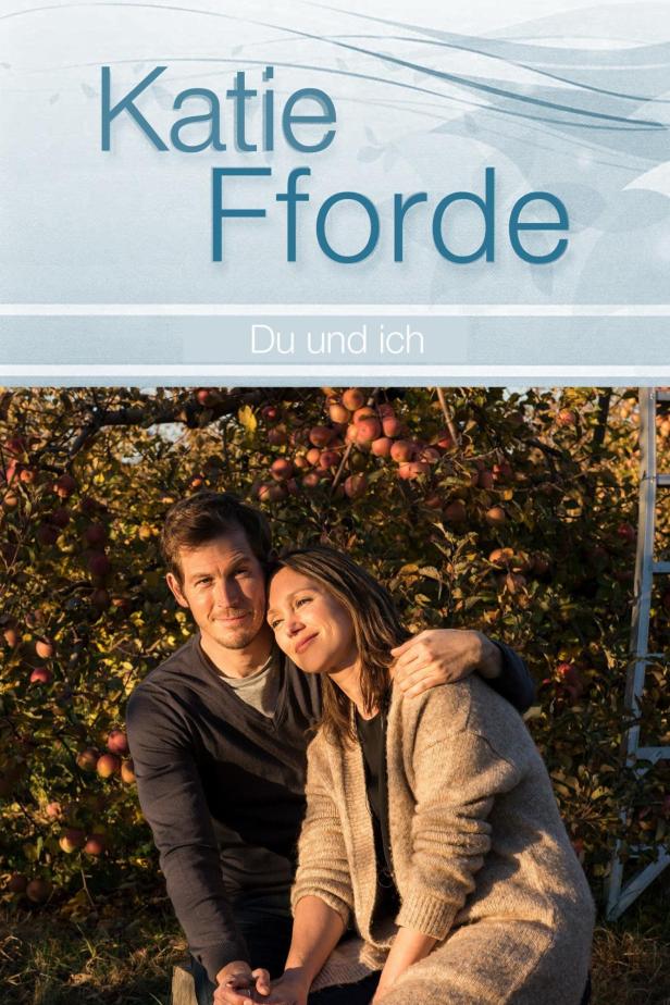 Ein Paar sitzt vor einem Apfelbaum; Buchcover „Du und ich“ von Katie Fforde.