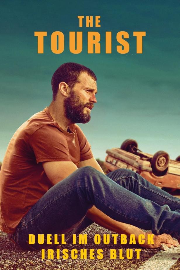 Ein Mann sitzt neben einem Autowrack in der australischen Wüste, Plakat für „The Tourist“.