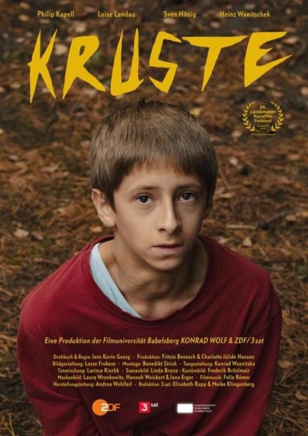 Das Filmplakat für „Kruste“ zeigt einen jungen Mann vor dem Hintergrund eines Waldes.