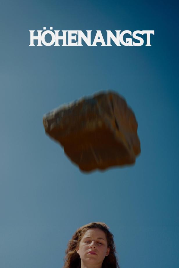 Eine Frau blickt nach oben zu einem schwebenden Felsen; Titel „Höhenangst“ im oberen Bildbereich.