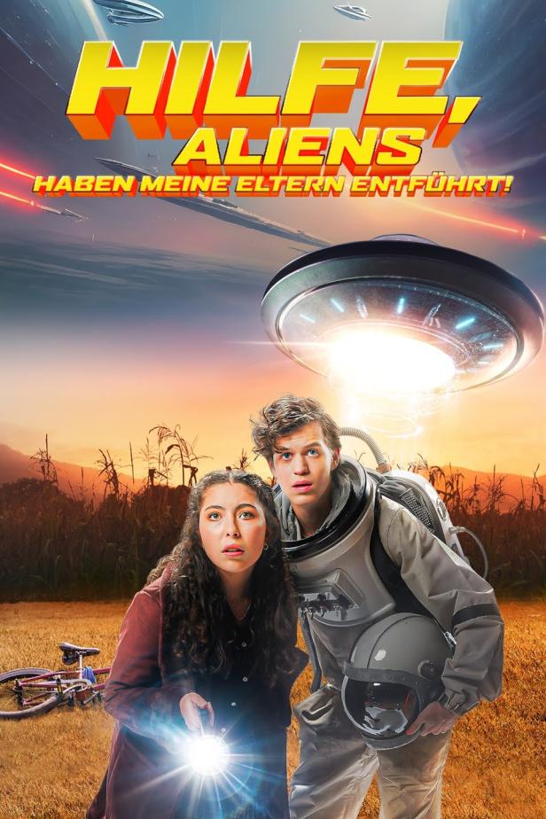 Ein Junge im Astronautenanzug und ein Mädchen blicken besorgt auf ein UFO über einem Feld.