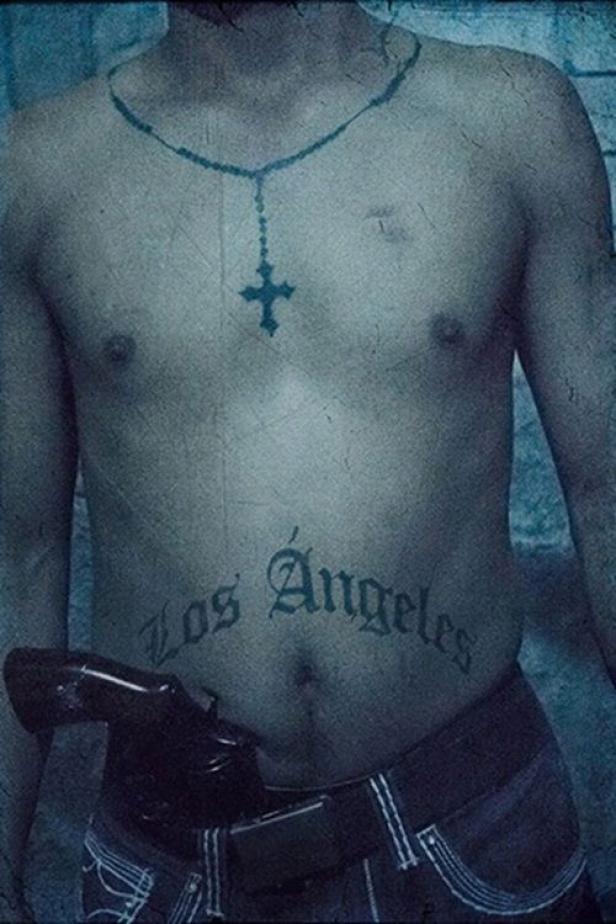 Ein Mann mit Tätowierungen und einer Pistole im Hosenbund.