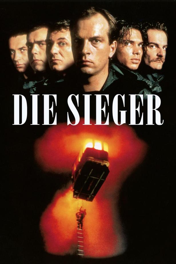 Das Filmplakat für „Die Sieger“ zeigt sechs Männer und einen brennenden Bus.