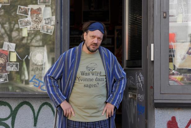 Charly Hübner steht in Filmrolle in einer offenen Tür von einem Geschäft