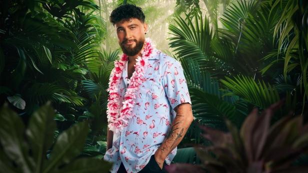 Umut Tekin mit Blumenkette um Hals vor KI-generiertem Dschungel