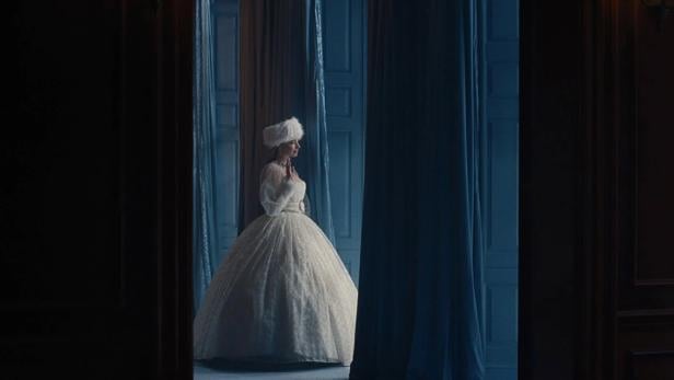 Margot Robbie mit weißem Kleid zwischen dunklen Vorhängen