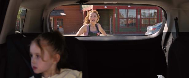 Frau läuft hinter einem Auto her, in dem ein kleines Mächen sitzt