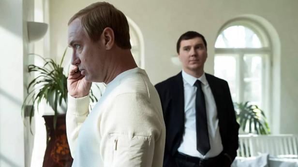 Jude Law steht als Putin telefonirend am Fenster - im Hintergrun Paul Dano als Baranov