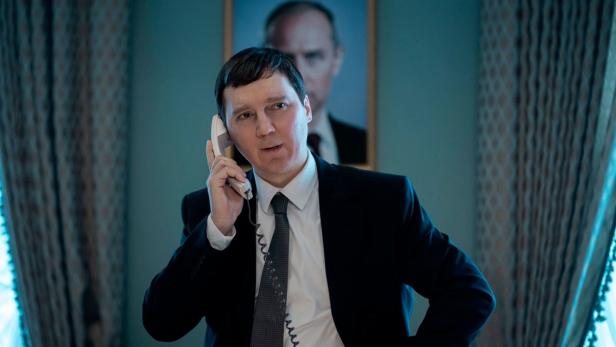 Paul Dano in Filmrolle am Telefon - im Hintergrund hängt Bild von Jude Law als Putin