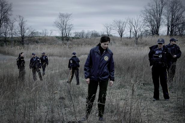 Polizisten suchen auf einer Wiese nach Spuren