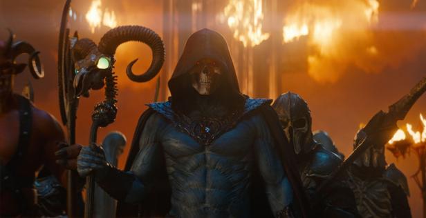 Skeletor mit Totenkopfmaske und Stab steht vor einer Armee in einer feurigen, düsteren Umgebung.