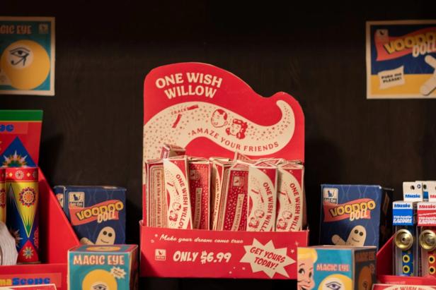 Ein Verkaufsaufsteller für „One Wish Willow“-Wunschknochen steht umgeben von Voodoo-Puppen- und Magic-Eye-Schachteln in einem Regal.