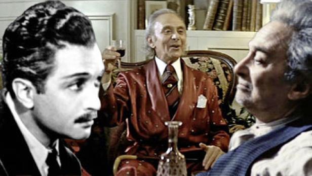 Drei Männer sitzen in einem Raum, einer hält ein Weinglas in der Hand.