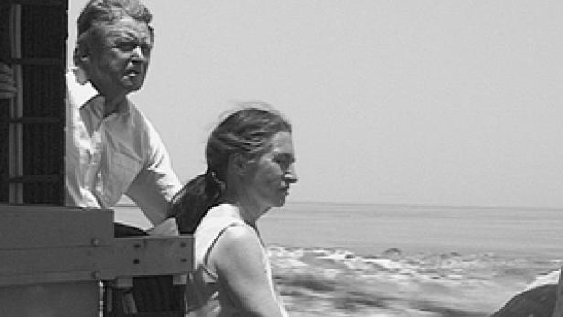 Ein Mann und eine Frau schauen von einem fahrenden Boot auf das Meer.