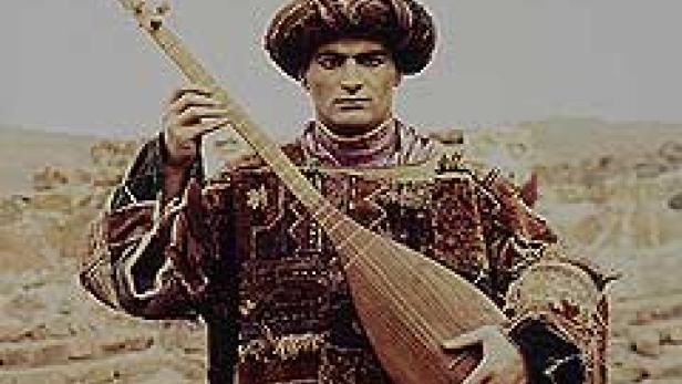 Ein Mann in traditioneller Kleidung hält ein Saiteninstrument in der Hand.