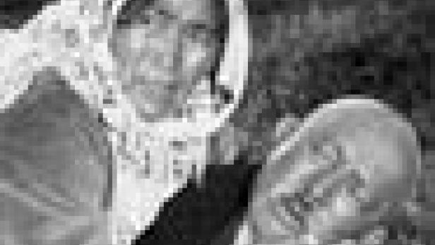 Eine ältere Frau hält den Kopf eines Mannes in ihren Händen.