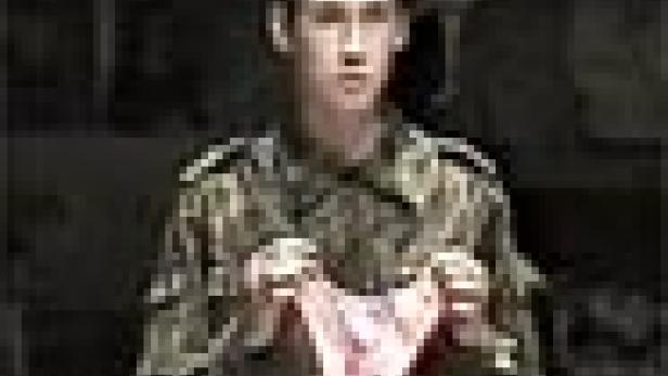 Ein Soldat in Uniform hält eine rosafarbene Unterhose hoch.