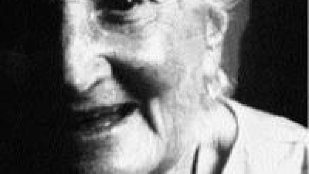 Schwarzweiß-Porträt einer älteren Frau, deren Gesicht zur Hälfte im Schatten liegt.