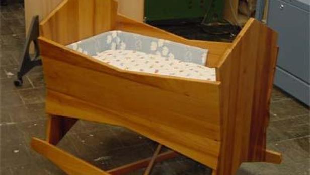 Eine hölzerne Babywiege mit einer gepolsterten Innenausstattung.