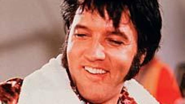 Ein lächelnder Elvis Presley mit einem Handtuch um den Hals.