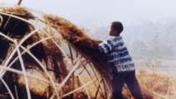 Ein Mann baut ein Haus mit einem Strohdach.