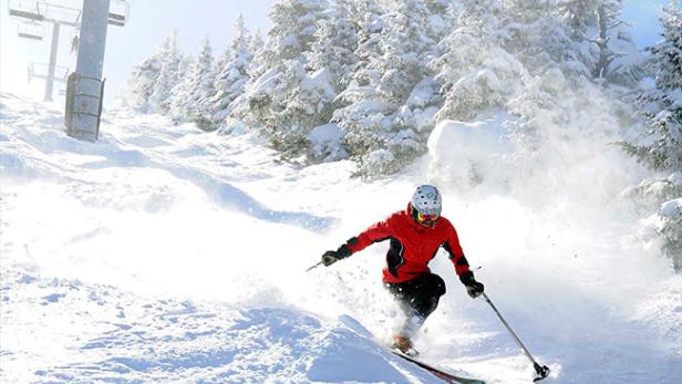 Ein Skifahrer fährt einen schneebedeckten Hang hinunter.
