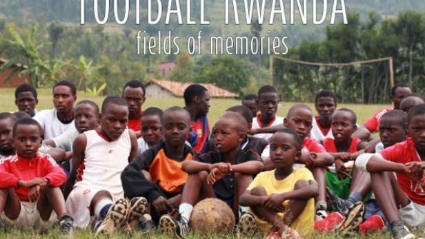 Eine Gruppe junger Fußballspieler sitzt auf einem Feld in Ruanda.
