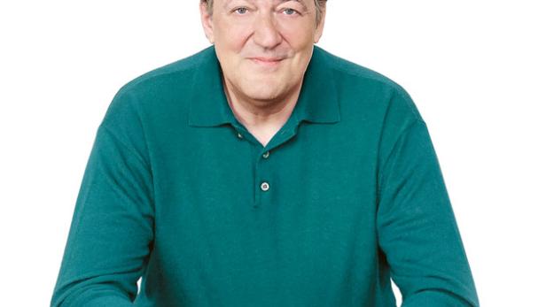 Porträt von Stephen Fry, der in einem grünen Pullover und brauner Hose sitzt.